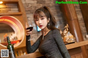A woman sitting on the floor next to a bottle of wine.
