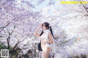 A woman in a pink bikini standing in front of a tree.