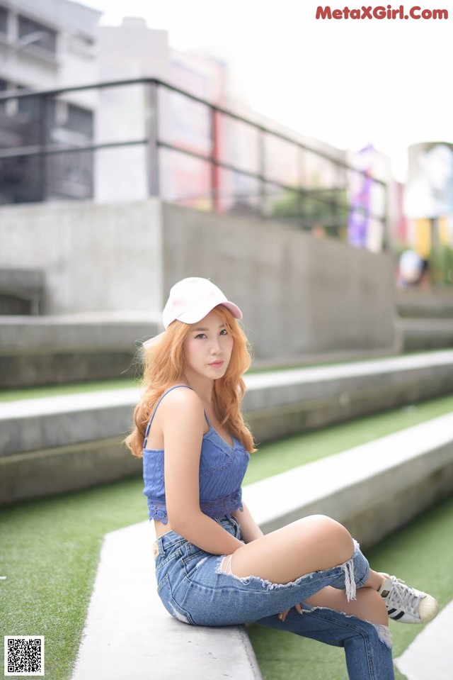 A woman sitting on the ground wearing a white hat.