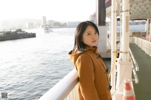 A woman sitting on top of a stone wall next to the ocean.