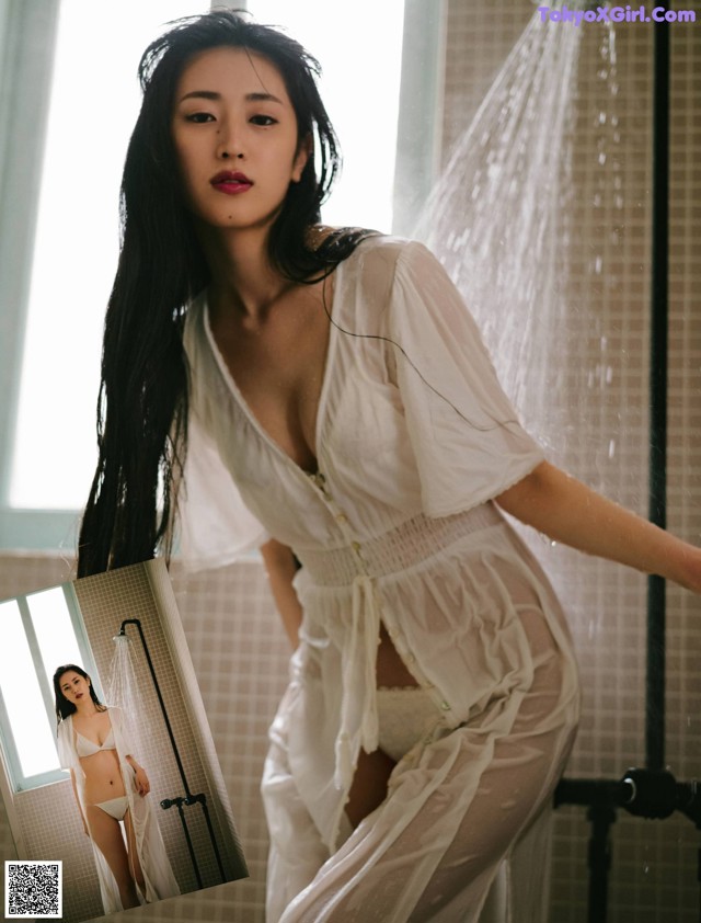 A woman in a white robe standing in a shower.