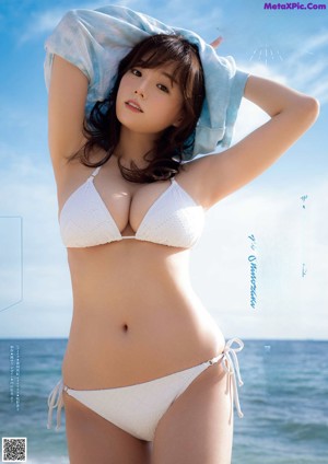 A woman in a white bikini laying on the beach.