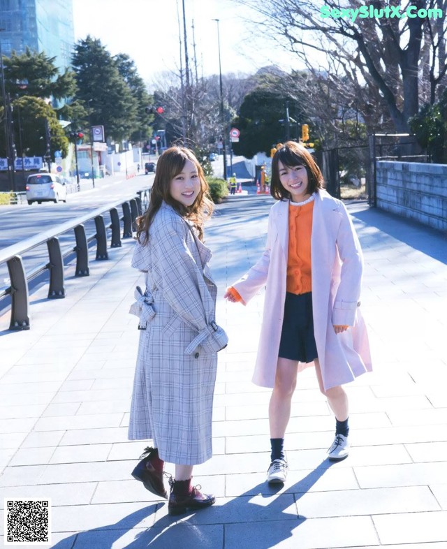 A couple of women standing next to each other on a sidewalk.