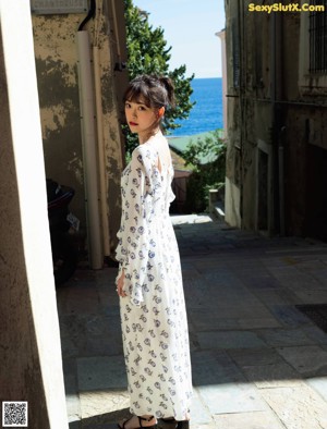 A woman in a white dress with blue flowers on it.