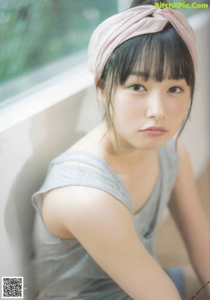A young woman leaning against a window with her legs crossed.