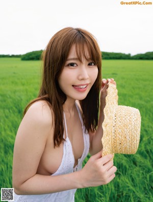 A woman in a white dress holding a straw hat.