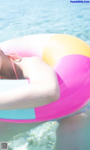 A woman in a pink bikini sitting on a wooden bench.