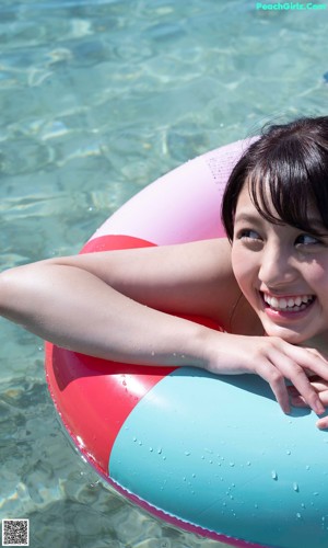 A woman in a bikini laying on an inflatable ring in the water.
