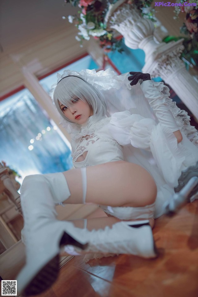 A woman in a white dress and white boots posing for a picture.