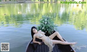 A woman sitting on a wooden dock next to a body of water.