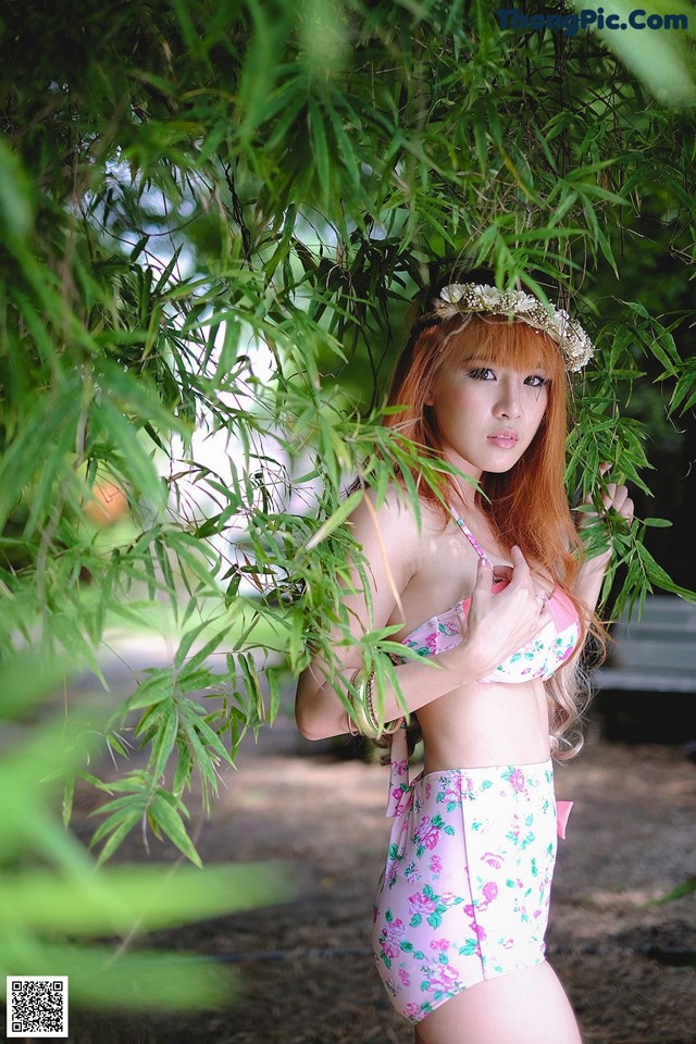 A woman in a pink bikini standing under a tree.