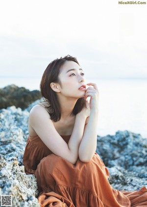 A woman sitting on a couch in a blue dress.