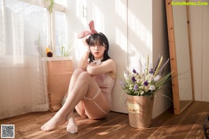 a woman in a pink bunny costume sitting on a mannequin