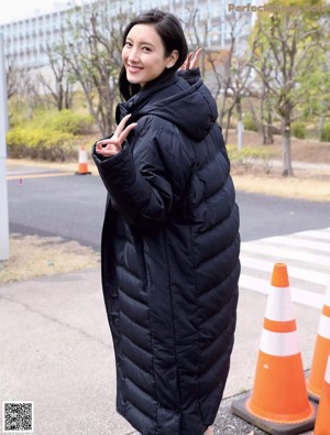 A woman in a black dress is posing for a picture.