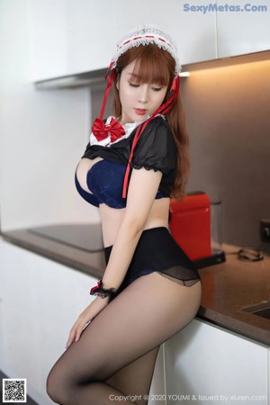 A woman in a red and black outfit is sitting on a couch.