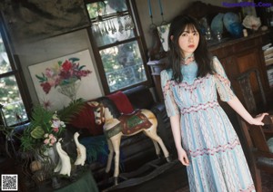 A woman with long black hair wearing a blue dress.