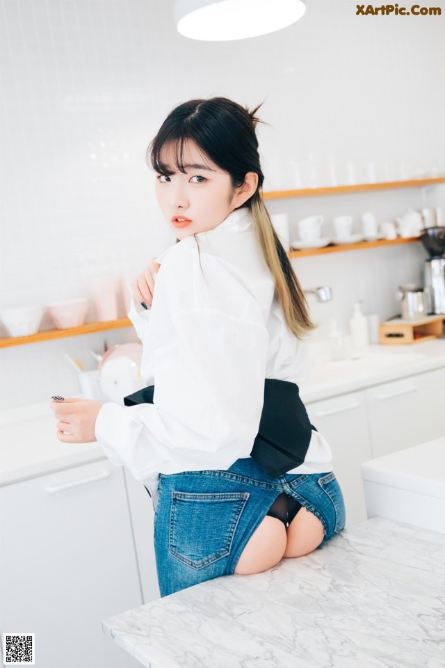 A woman sitting on top of a counter in a kitchen.
