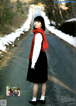 A woman in a school uniform standing by a window.