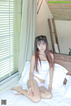 A woman laying on top of a bed in a white and blue outfit.