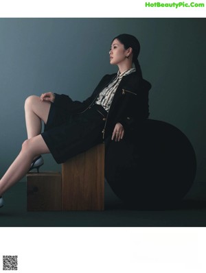 A woman standing on top of a pedestal holding a handbag.