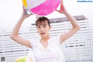 A woman holding a large pink and blue beach ball.