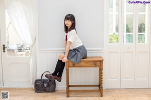 A woman in a school uniform sitting on a chair.
