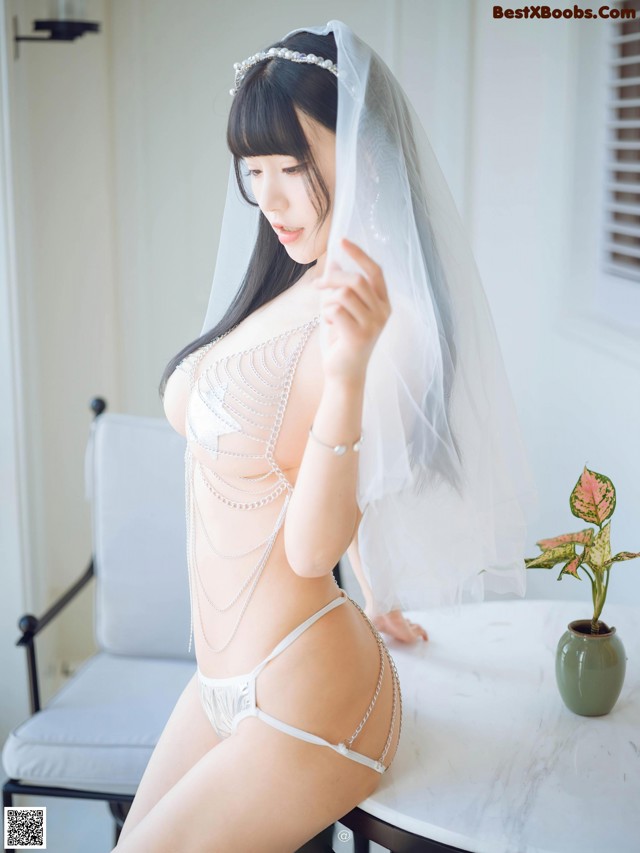 A woman in a white lingerie sitting on a table.