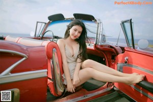 A woman sitting in the back seat of a red car.