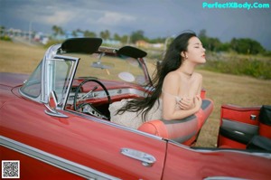 A woman sitting in the back seat of a red car.