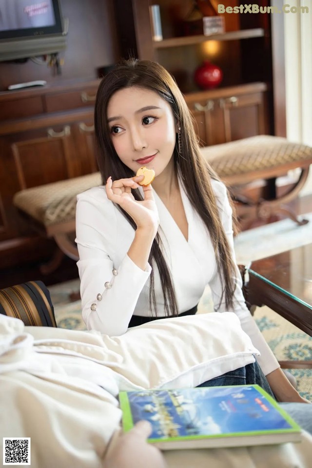 A woman sitting on a couch eating a piece of food.