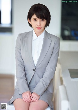 A woman in a school uniform sitting on the floor.