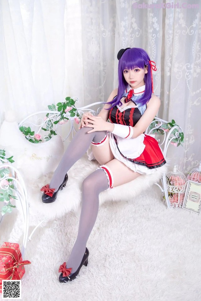 A woman in a maid outfit sitting on a white chair.