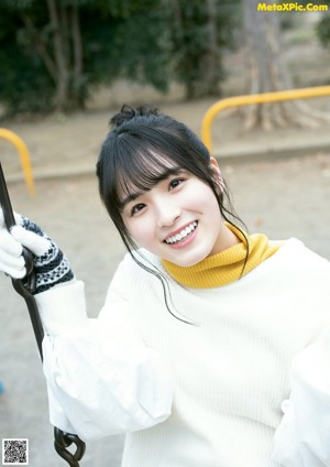 A woman sitting on a wooden bench wearing a white sweater.