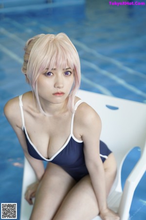 A woman in a bathing suit sitting on a chair in a pool.