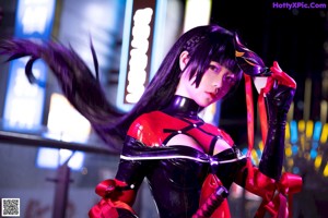 A woman in a black and red outfit holding a white mask.