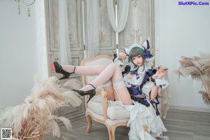 A woman in a blue and white dress sitting on a couch.